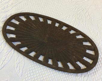 Antieke gietijzeren houtkachel platte onderzetter met gecanneleerd zonnestraalontwerp in het midden. Geroest primitief en rustiek stuk.