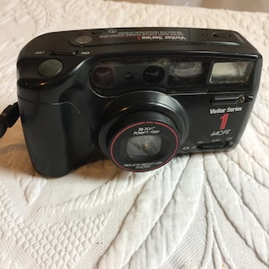 Könnte beinhalten: Eine schwarze Vivitar Series 1 440PZ Kamera mit einem Rot-Augen-Reduktionssystem und einem 38-70mm Powerzoom-Objektiv.