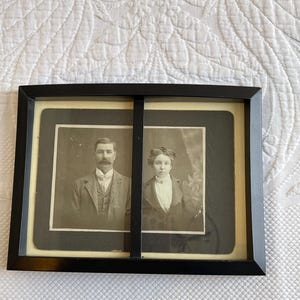 Schwarzer Doppelbilderrahmen. Schwarzer Rahmen mit leicht gebogener Vorderseite und alten viktorianischen Bildern von Lady & Gentleman. Schwarzer Samt und Tischplattenständer.