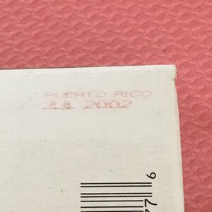 Puede incluir: Una etiqueta blanca con un sello rojo que dice "Puerto Rico 11.1.2002" y un c&oacute;digo de barras negro.
