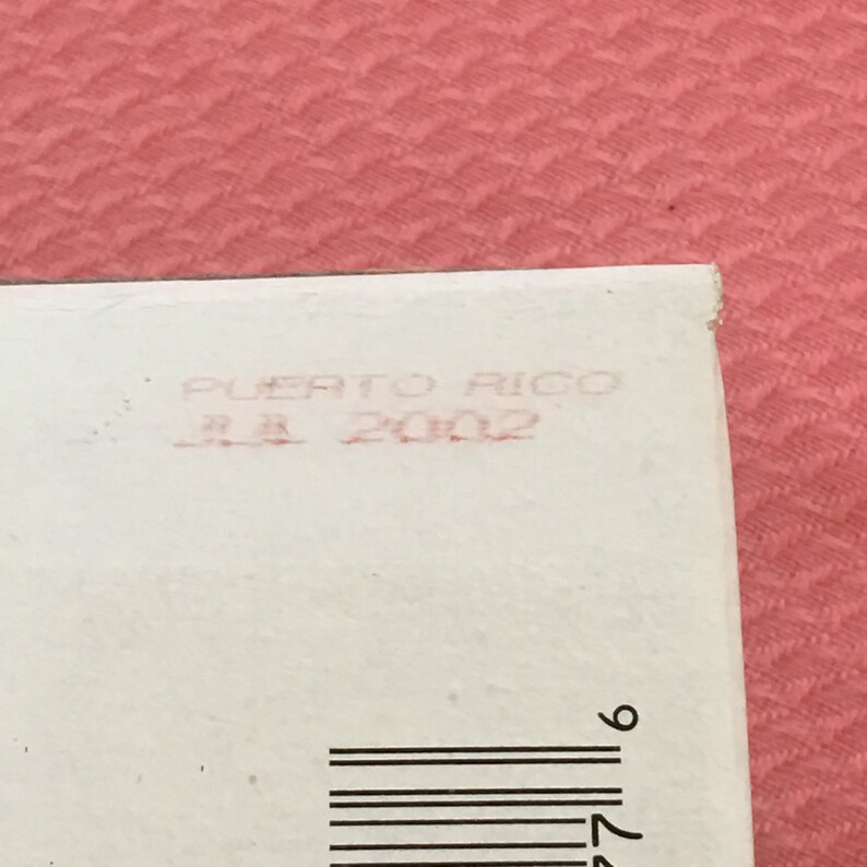 Puede incluir: Una etiqueta blanca con un sello rojo que dice "Puerto Rico 11.1.2002" y un c&oacute;digo de barras negro.