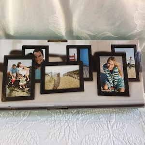 Puede incluir: Un conjunto de seis marcos de fotos negros, cada uno con una fotografía diferente. Las fotos muestran varias escenas, incluyendo una familia en la playa, una persona sonriendo y un paisaje de playa. Los marcos están dispuestos sobre una superficie blanca.