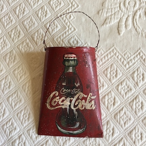 Kieszeń ścienna Vintage Coca Cola. Ręcznie malowana butelka Coca-Coli z napisami z przodu na czerwonym tle. Wieszak druciany. Urocza kieszeń ścienna.