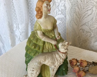 Vintage Chalkware Lady y su perro figura escultura. Cabello rubio, vestido fruncido verde y guantes, sosteniendo su correa de perro. Gran parada de la puerta.