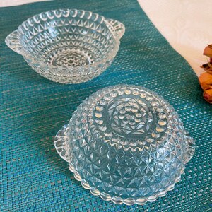 May include: Two clear glass bowls with a diamond pattern and a beaded rim. The bowls have handles on either side.