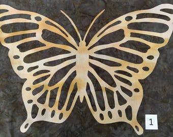 May include: A cutout of a butterfly with a detailed design. The butterfly is a light brown color and is set against a dark brown background.
