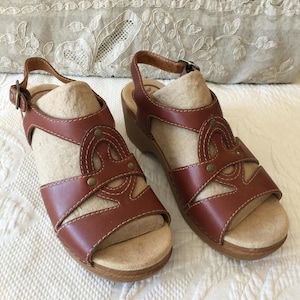 Dansko Sigrid Brown Wedge Sandals Shoes 98197762200, Size 37 or 6 1/2. Leather Upper with Oval Woven Front Design with Hobnails.