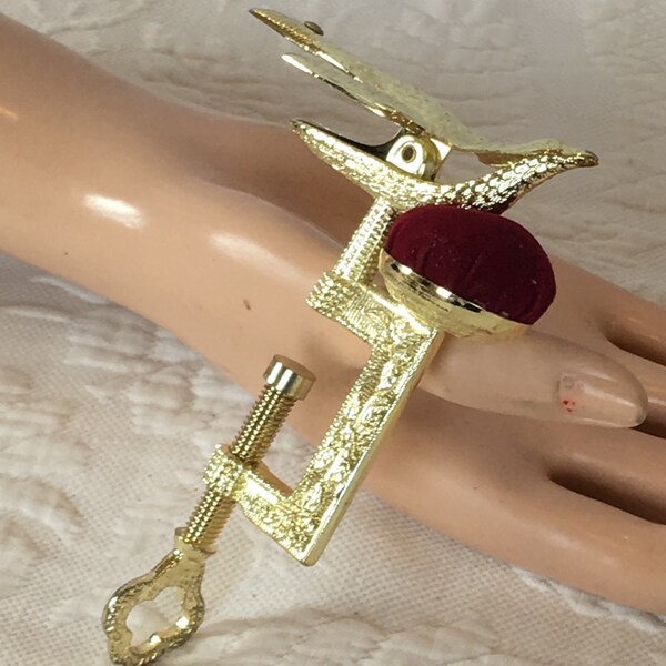 Gold Sewing Bird with Red Pin Cushion and Screw Clamp. Reproduction Sewing Bird with Beak Holder, Red Pin Cushion and Screwing Clamp.
