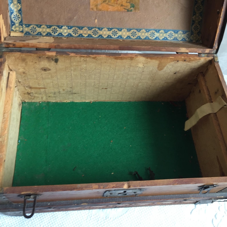 Puede incluir: Un cofre de madera antiguo con un forro de fieltro verde. El cofre tiene un pestillo y bisagras de metal. El interior del cofre est&aacute; vac&iacute;o.
