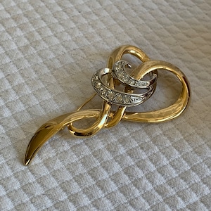 May include: A gold-toned brooch with a swirling design and clear rhinestones.