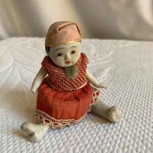 Vintage Oriental Baby Porzellanpuppe mit rotem Kleid mit Spitze am Saum. Charmante Puppe zum Aufstellen.