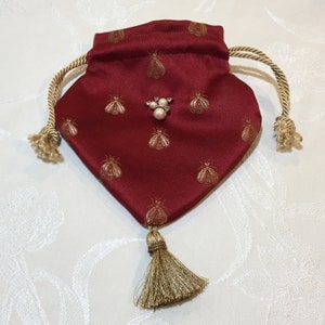Retícula de abeja hecha a mano roja con abejas cosidas en oro en tela. Forro de seda sintética roja o seda canela. Cordón trenzado dorado y borla.
