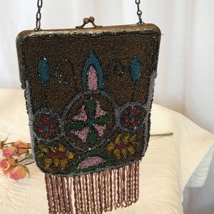 Torebka wieczorowa z artystycznymi koralikami w stylu vintage. Koraliki w kolorze złotym, niebieskim, czarnym, czerwonym, różowym, zielonym i lawendowym. Frędzle z koralików w kolorze lawendowo-brązowym. Podszewka z szarego jedwabiu.