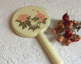 Miroir vintage Merle Norman Mirror. Miroir à main en plastique jaune dans un étui de protection avec fleurs roses et feuilles vertes.