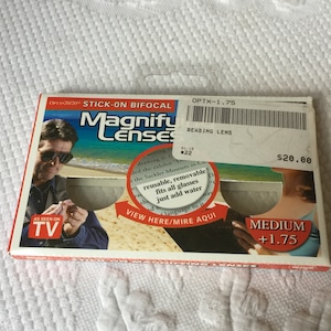 Könnte beinhalten: Eine Verpackung für Stick-On Bifocal Magnify Lenses, die einen Mann mit Sonnenbrille zeigt, der die Linsen zum Lesen verwendet. Die Verpackung enthält den Text "OPTX-1.75 Leselinse" und "20,00 €".