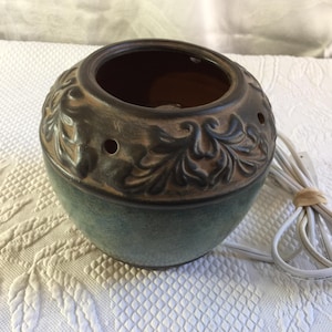 May include: A ceramic essential oil diffuser with a teal base and a brown, floral-patterned top. The diffuser has three small holes and a power cord.