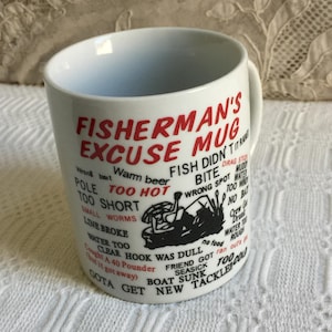 以下が含まれることがあります： 赤と黒で「FISHERMAN'S EXCUSE MUG」と書かれた白いセラミックマグ。マグには、釣りに関するさまざまな言い訳と、漁師の黒いグラフィックが描かれたユーモラスなデザインが施されています。