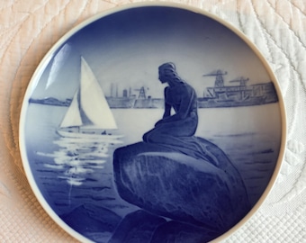Vintage Royal Copenhagen Danmark. Den lilla sjöjungfrun sitter på en klippa med en segelbåt i närheten. Köp tallrik eller skål eller 1 liten fyrkantig tallrik.