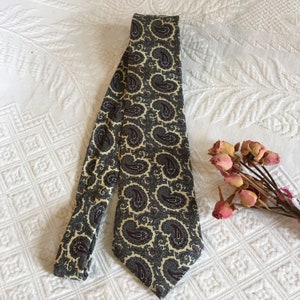 Puede incluir: Una corbata con estampado de paisley con fondo crema y diseños de paisley azul oscuro y burdeos.