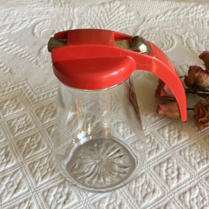 Vintage Honig oder Sirup Jar Dispenser. Daumen-Slide-Open-Spout. Sunburst Design auf der Unterseite des Jar.