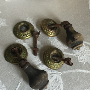 Op de afbeelding: Vier antieke messing kastknoppen met groene accenten en houten handvatten. De knoppen hebben een geometrisch ontwerp en zijn in goede staat.