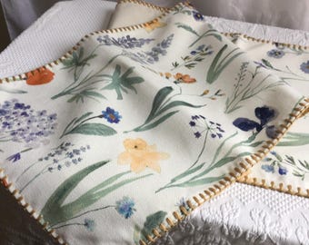 Vintage-Tischläufer mit Blumenmuster und goldfarbener Ziernaht am Rand. Weißer Hintergrund mit roten, blauen und grünen Akzenten. 35,5 x 183 cm.