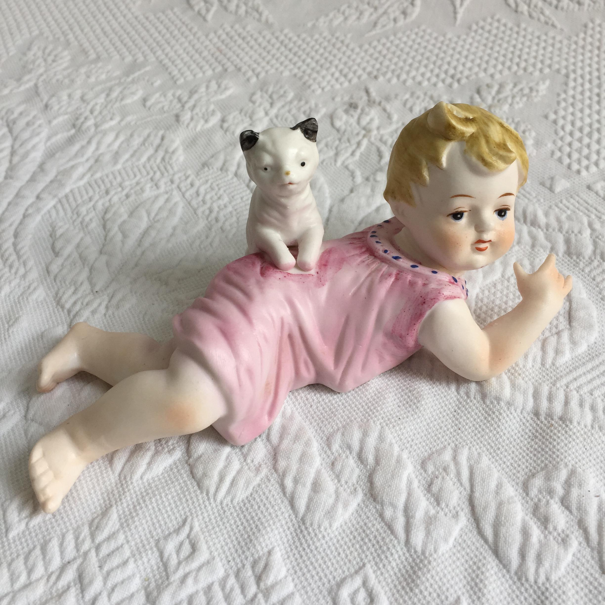 ヴィンテージ磁器の赤ちゃんと猫。赤ちゃんがうつ伏せになり、猫が