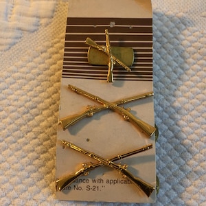 Zabytkowa wojskowa przypinka do kołnierza z II wojny światowej z 1942 roku. Oficerska przypinka piechoty Rothco. Skrzyżowane karabiny z uchwytami do mocowania. Oferta dotyczy jednej sztuki.