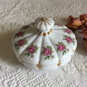 Cómoda vintage con motivo de rosas en forma de corona y adornos de cuentas y triángulos dorados. Encantadora cómoda de porcelana.