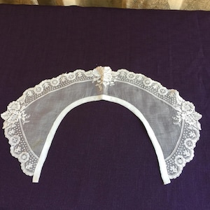 以下が含まれることがあります： 繊細なレースの襟で、縁はギザギザになっており、花柄の刺繍が施されています。襟は繊細な生地で作られており、柔らかく女性らしい印象です。