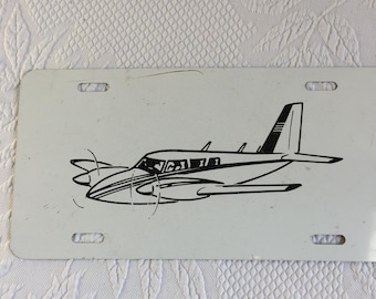 Vintage Blech-Flugzeugkennzeichen. Piper PA-34 Seneca Twin Motor Flugzeug Zeichnung auf weißem Weißblech.