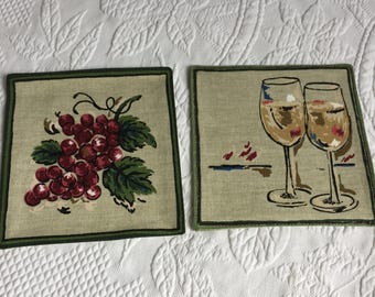 Vintage-Paar bemalter Weinuntersetzer aus Leinen. Einer mit einer Weintraube, der andere mit zwei Weingläsern. Schützen den Tisch vor Kondenswasserbildung.