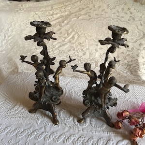 Antique Bronze Candlestick Holders With Three Boys Holding Birds Leaning Away From Center. Three Legged Base. Molded Leaves and Swirls.