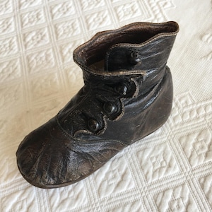 Antiker viktorianischer Babyschuh aus schwarzem Leder mit 4 Knöpfen und ausgebogter Pull-to-Side-Klappe. Ideal für ein Display.