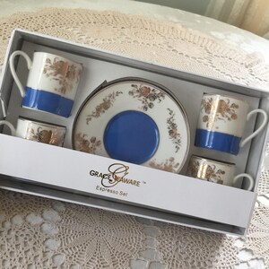 May include: An espresso set in a white box. The set includes four small cups, a saucer, and a box. The cups and saucer are white with gold floral designs and blue accents. The box has the text "GRACE SEAWARE Espresso Set".