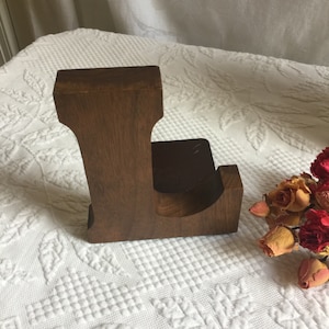 Suporte para livros em L de madeira vintage. Base de metal com enchimento de feltro na parte inferior e lateral de um suporte para livros com letra L de madeira.