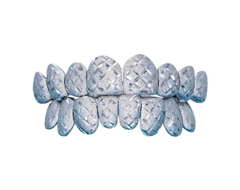 Puede incluir: Grillz plateados con un diseño texturizado de diamantes. Los juegos de dientes superiores e inferiores se muestran sobre un fondo blanco. Los grillz son un accesorio de moda.