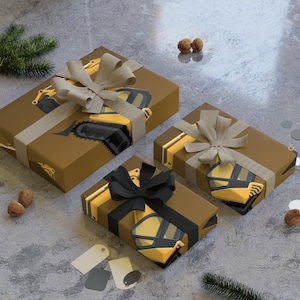 May include: Three wrapped gifts with brown paper and construction vehicle graphics. Each gift is tied with a ribbon, one with a black bow, and the others with beige bows. The gifts are on a grey surface.