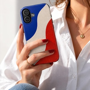 May include: A smartphone case featuring a blue, white, and red design. The case has a curved pattern and is held in a person's hand. The phone case is a protective accessory for a mobile device.