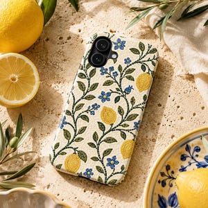 Pode incluir: Uma capa de telefone com fundo creme com um padr&atilde;o repetido de lim&otilde;es amarelos, flores azuis e vinhas verdes. A capa tem um recorte para uma c&acirc;mera de lente dupla. A imagem tamb&eacute;m inclui lim&otilde;es, folhas e um prato decorativo.