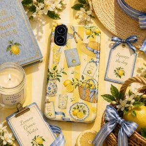 May include: A smartphone case featuring a yellow and white striped pattern decorated with illustrations of lemons, a straw hat, a wicker basket, a blue and white vase, a candle, and a book titled The Lemon Grove Club with a blue ribbon.