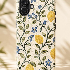 Puede incluir: Funda de teléfono con diseño de mosaico de limones amarillos, flores azules y hojas verdes sobre fondo crema. La funda tiene un recorte para la cámara y detalles laterales negros.
