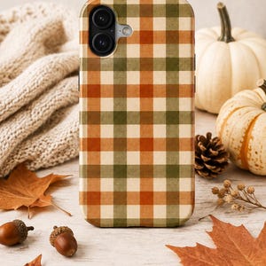 Op de afbeelding: Een rechthoekig smartphonehoesje met een herhalend ruitpatroon in tinten van gebrand oranje, olijfgroen en crème. Het hoesje heeft een uitsparing in de linkerbovenhoek voor een dubbel camerasysteem en een kleine ronde opening voor de flitser.