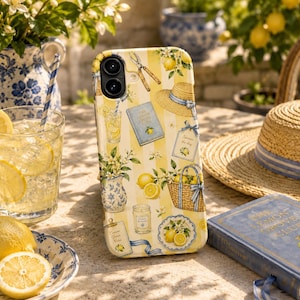 May include: A smartphone case featuring a yellow and white vertical striped pattern decorated with illustrations of lemons, a straw hat, a blue book titled The Lemon Grove Club, a woven basket, a candle, garden shears, and floral arrangements.