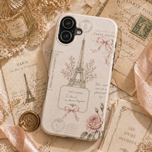 May include: A cream-colored phone case featuring a Parisian theme with the Eiffel Tower, pink roses, and the text "Très Chère". The case is surrounded by vintage postcards, a perfume bottle, and a wax seal.