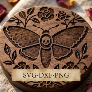 May include: A circular dark brown wooden coaster featuring a laser-engraved design of a moth with a skull on its thorax, surrounded by floral patterns, leaves, and small stars. A rectangular parchment-colored label displays the text SVG·DXF·PNG.