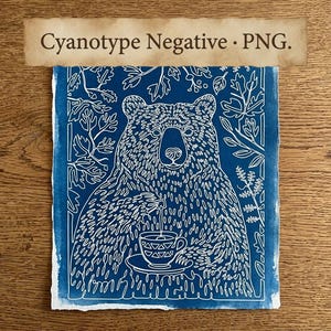 May include: A cyanotype print on paper featuring a white line art illustration of a bear holding a teacup against a deep blue background. The bear is surrounded by foliage patterns. The text Cyanotype Negative • PNG. is printed at the top.