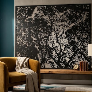 Pode incluir: Uma cena de sala de estar moderna com uma poltrona mostarda e um cobertor bege. Uma grande obra de arte em preto e branco com silhuetas de árvores está pendurada na parede. Um banco de madeira abriga uma lâmpada, livros e um relógio.