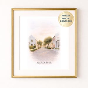May include: A framed watercolor print of a street scene in Alys Beach, Florida. The artwork features white buildings, cobblestone streets, and trees under a soft, pastel sky. The print is in a gold frame and includes the text "Alys Beach, Florida."