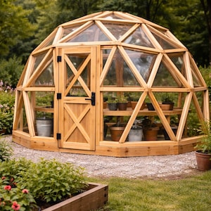 Pode incluir: Uma estufa de cúpula geodésica construída com uma estrutura de madeira clara e painéis transparentes. A estrutura apresenta uma porta central de madeira com design de reforço em cruz e ferragens pretas, abrigando várias plantas em vasos.